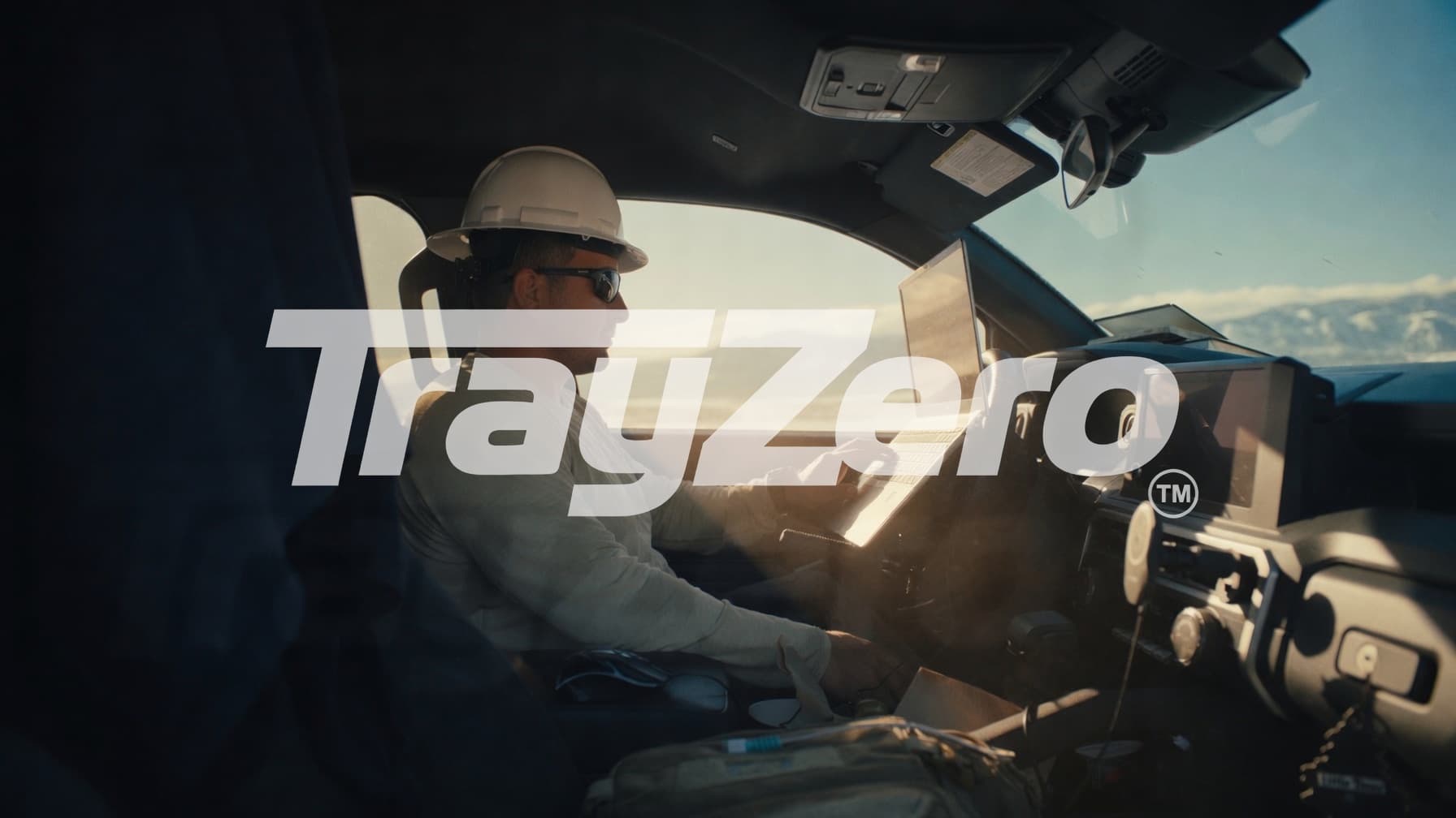 TrayZero demonstration video thumbnail — professional using a laptop in a parked vehicle